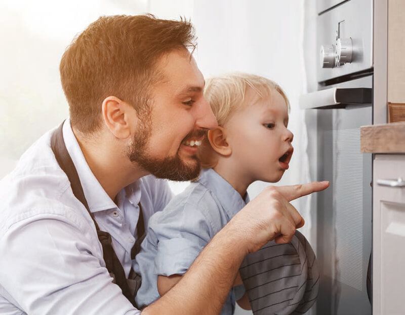 Vater zeigt seinem Kind einen Backofen Vater zeigt seinem Kind einen Backofen